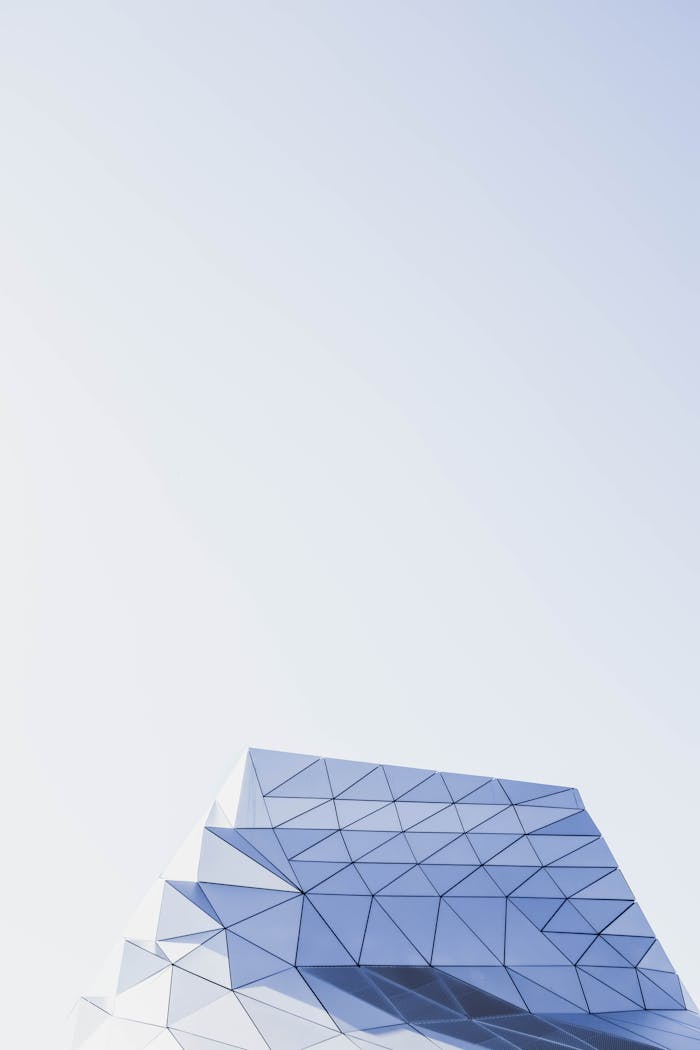 A minimalist view of a modern building with geometric patterns against a clear blue sky.
